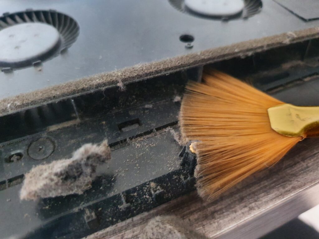 Técnico limpiando el interior de un notebook sucio, eliminando polvo acumulado en los ventiladores y componentes.